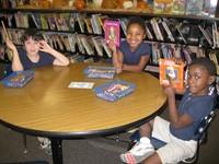 Three TCS students holding up library books 